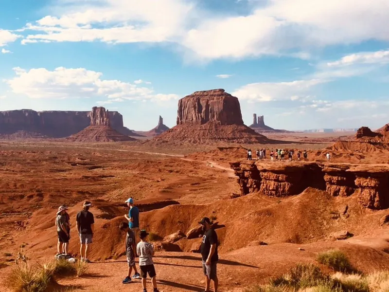 Open-air jeep driving past the Mittens buttes on a Monument Valley backcountry jeep tour with a Navajo guide, Arizona
