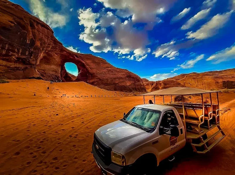 Navajo guide leading a 4x4 jeep tour past red sandstone buttes in Monument Valley Navajo Tribal Park, Utah