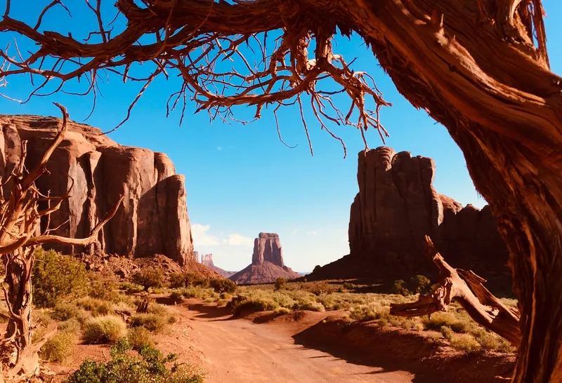 Jeep parked beneath a sandstone arch on a Monument Valley extended backcountry jeep tour with Navajo guide, Arizona